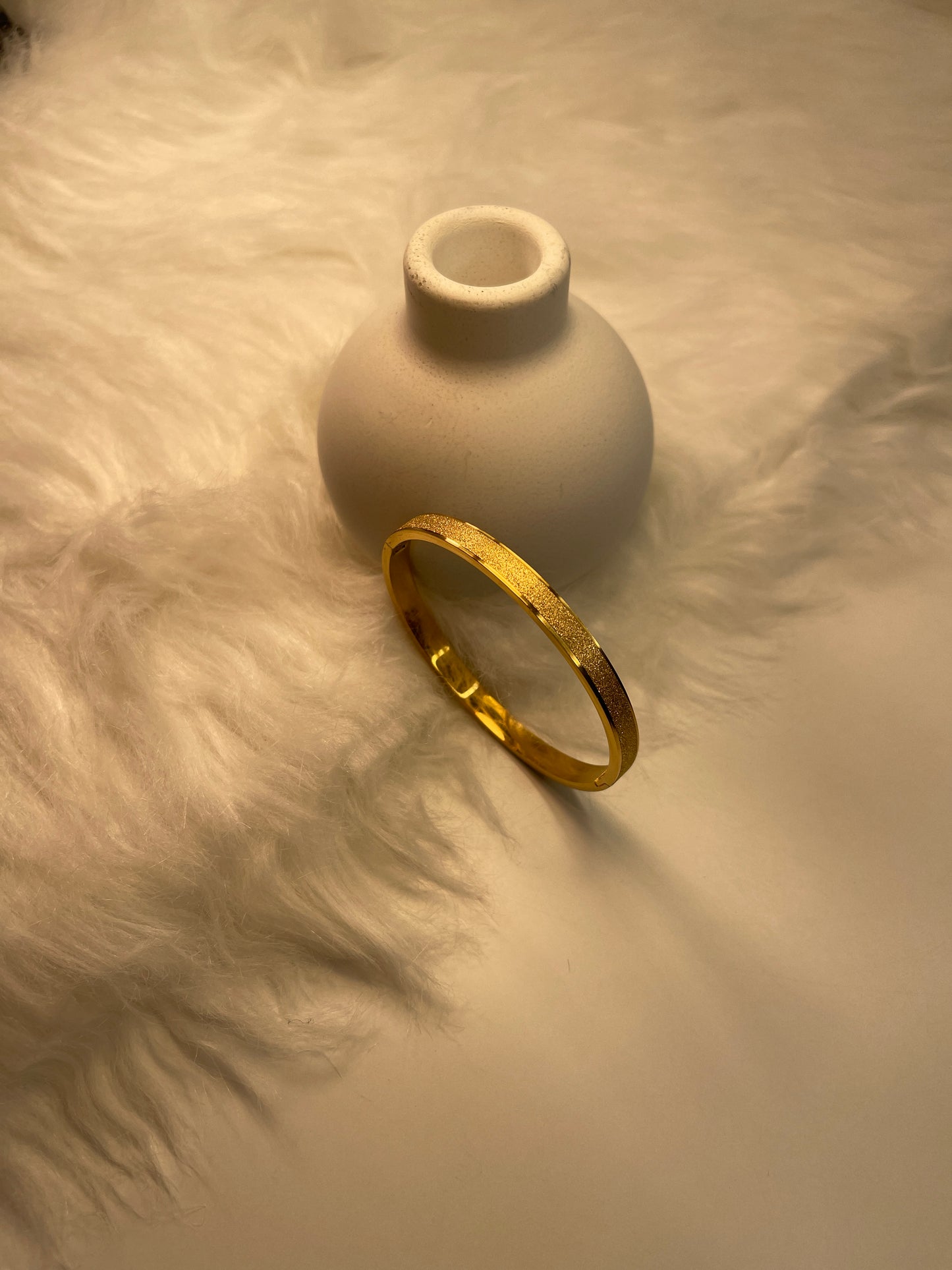 Gold Frosted Bangle on a textured beige surface