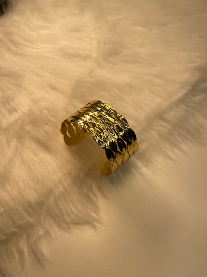 Gold bracelet on a textured beige surface