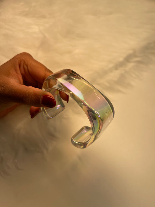 transparent iridescent Clear glass bangle held by a hand against a neutral background