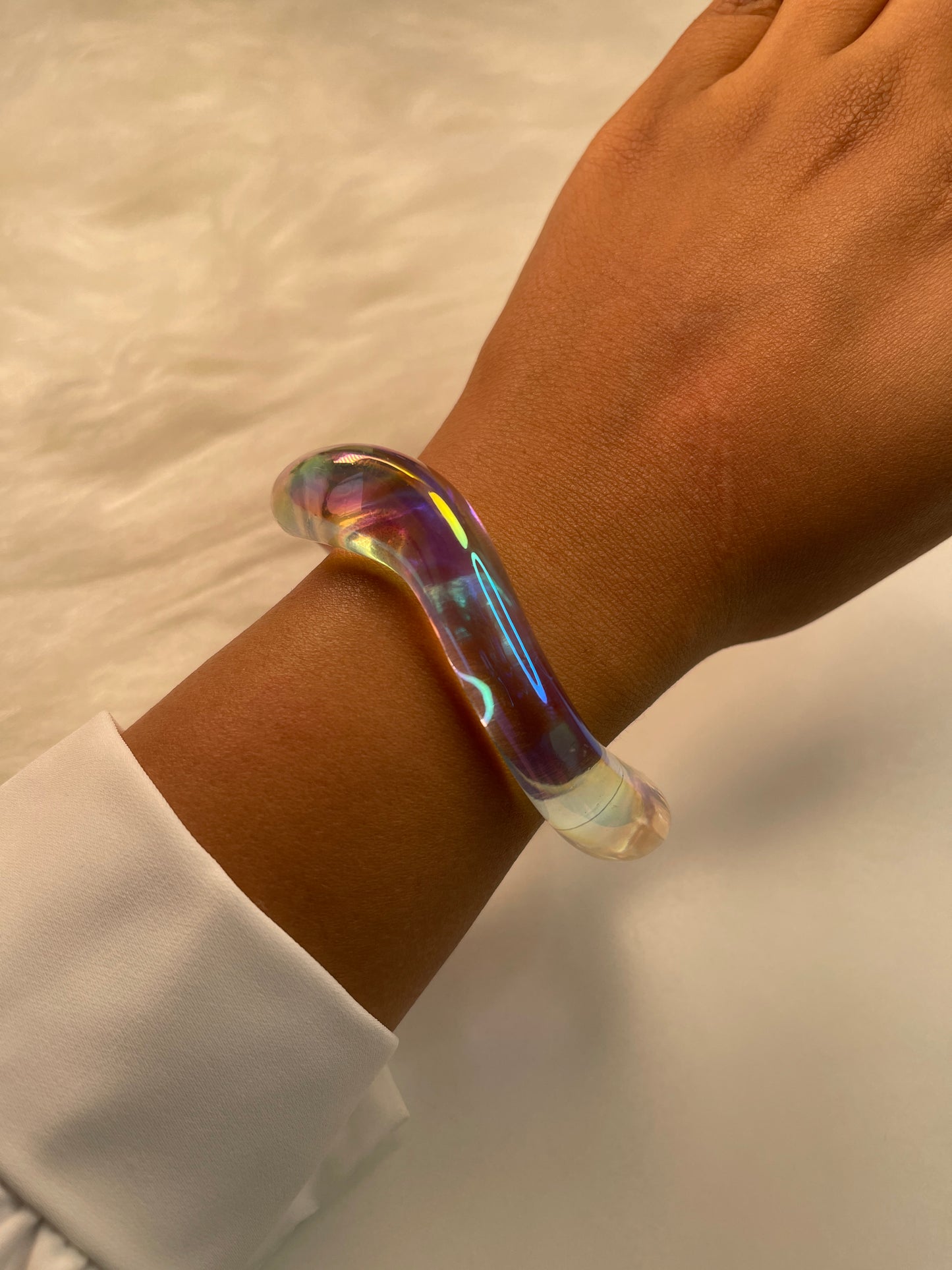 Iridescent bracelet on a wrist with a neutral background