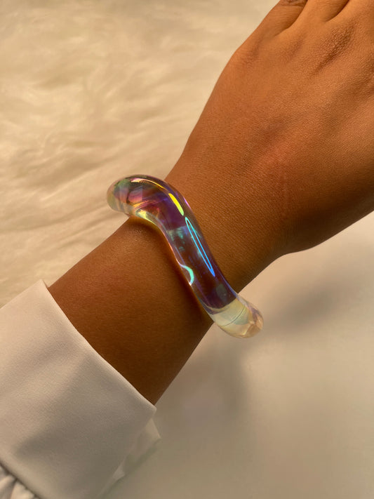 Iridescent bracelet on a wrist with a neutral background