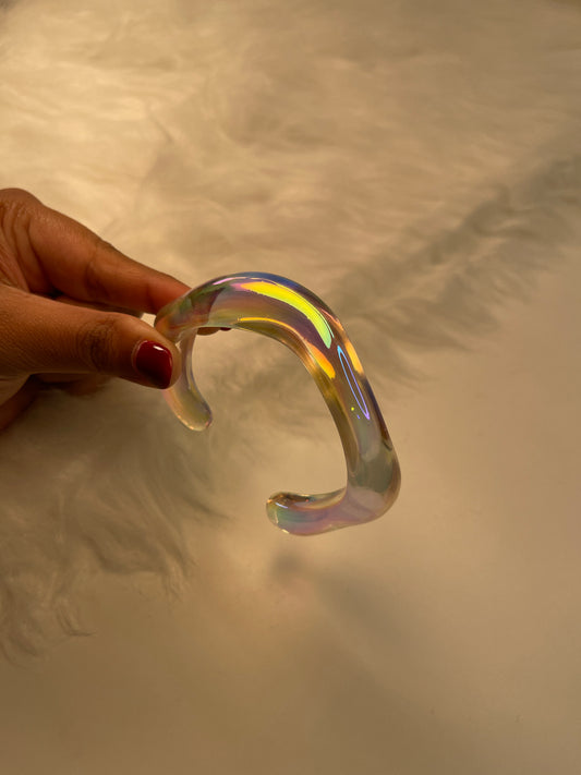 Hand holding a transparent, iridescent object against a neutral background