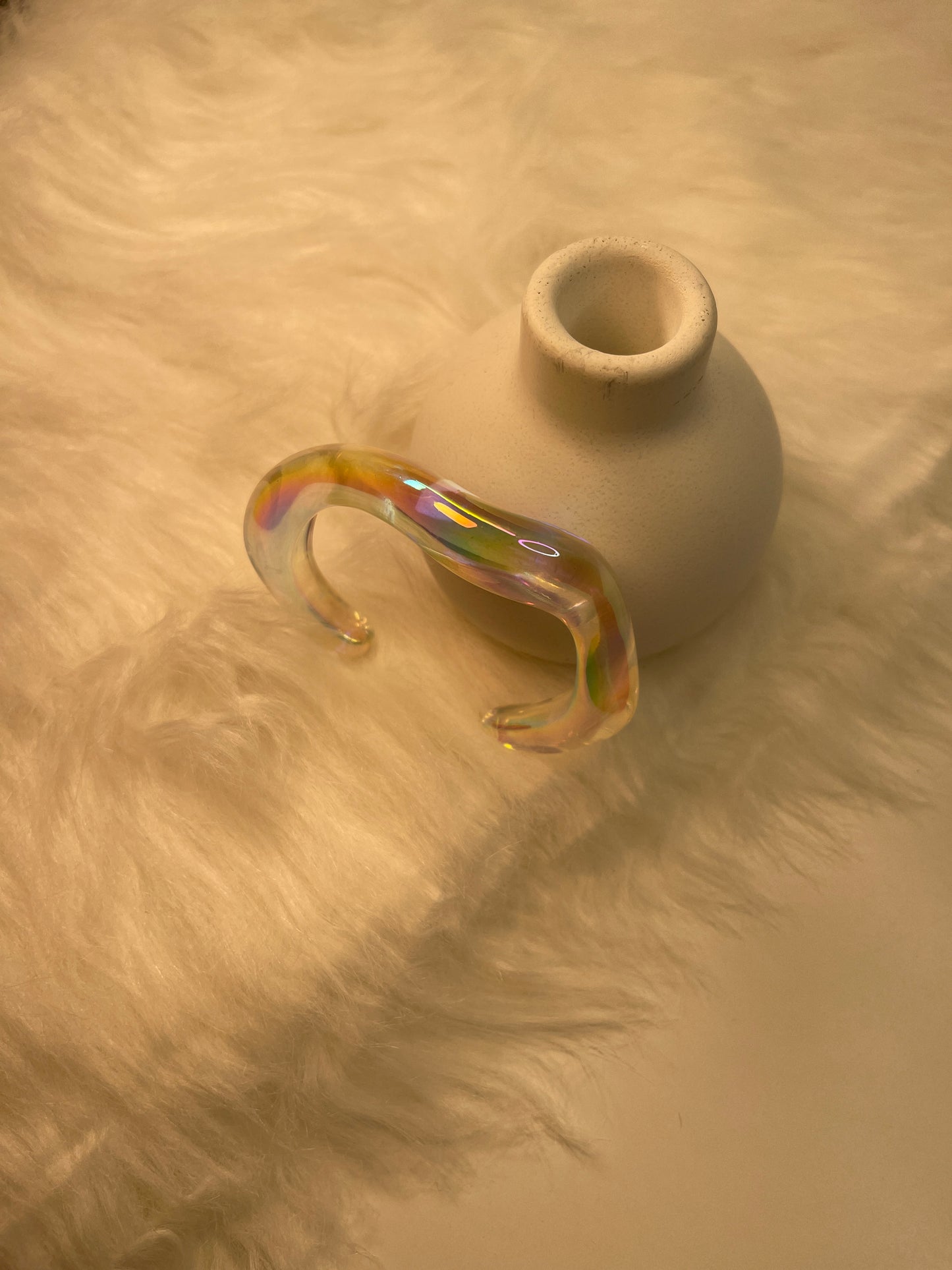 Transparent Bracelet with rainbow iridescence on a textured beige surface