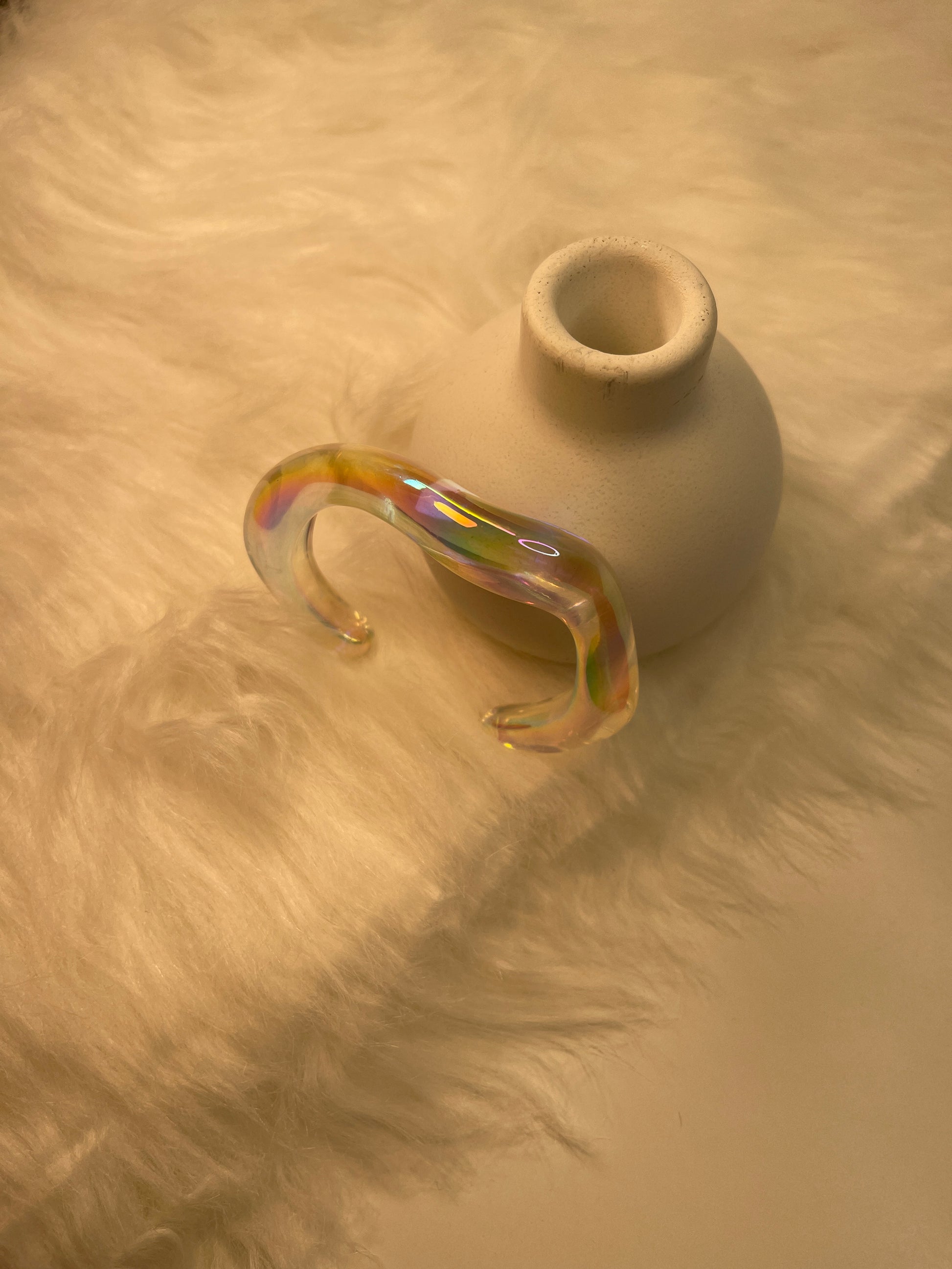 Transparent Bracelet with rainbow iridescence on a textured beige surface