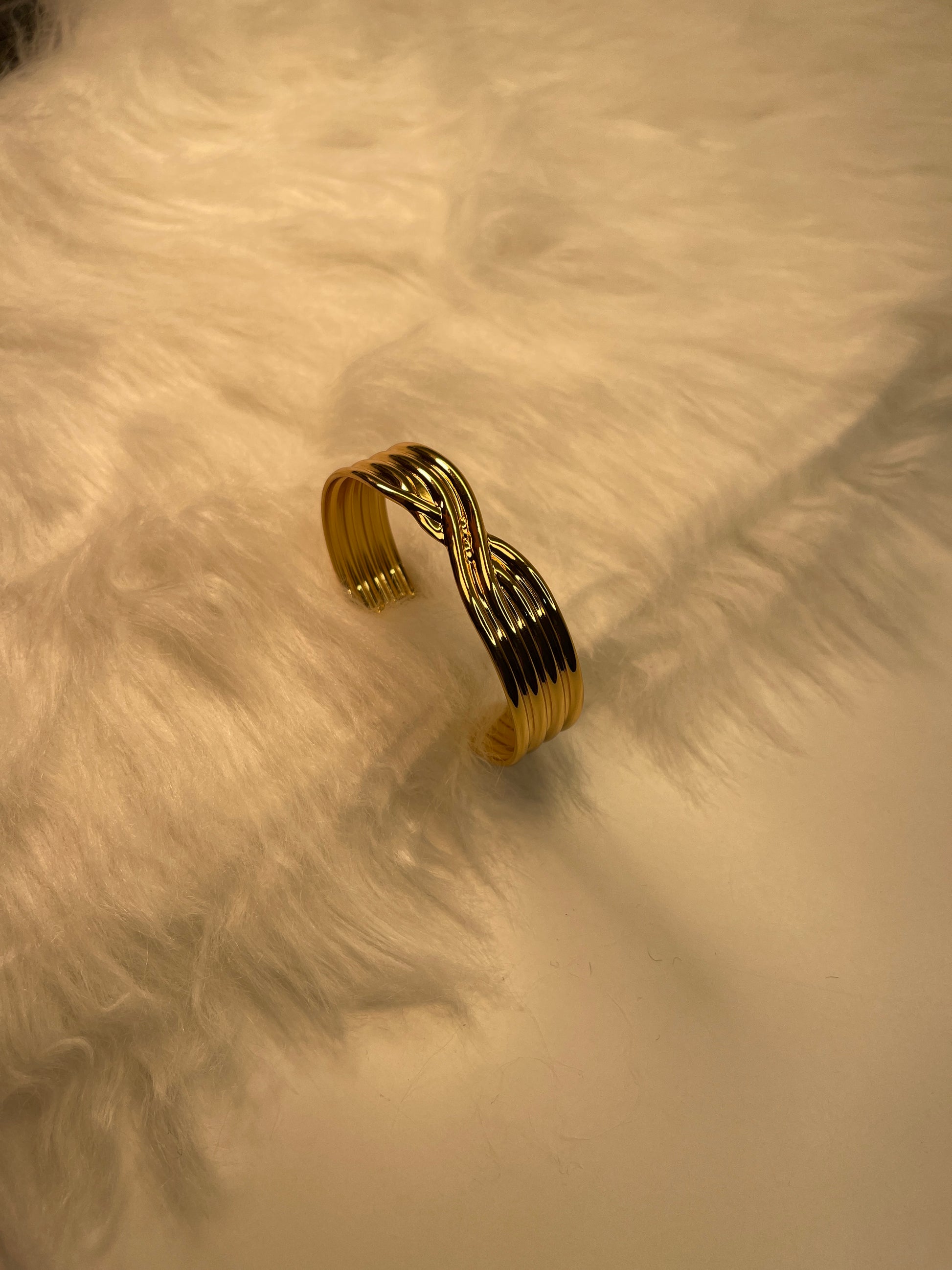Gold bracelet on a textured beige surface