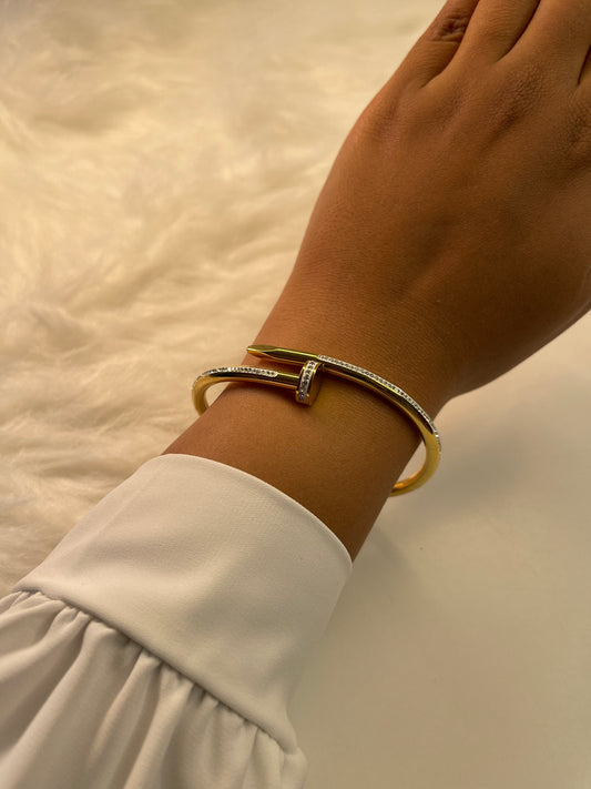 Hand wearing a gold bracelet on a light background