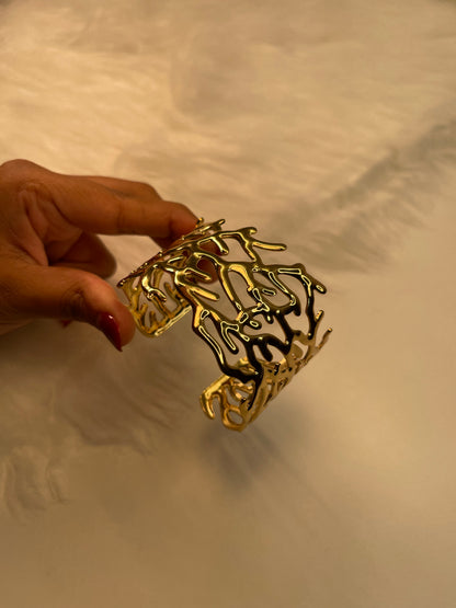 Gold Bracelet Coral held by a hand against a neutral background