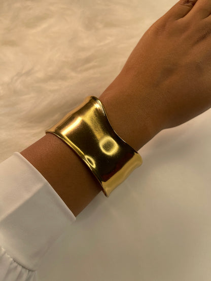 Gold bracelet on a wrist with a white background