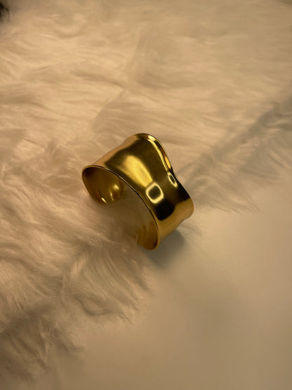 Gold Cuff Bracelet on a textured beige surface