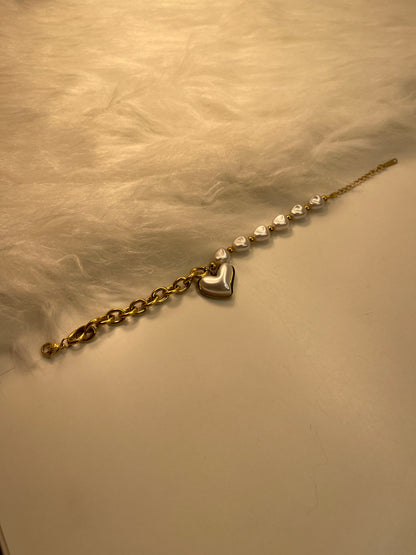 Gold chain pearl with heart-shaped clasp on a beige background