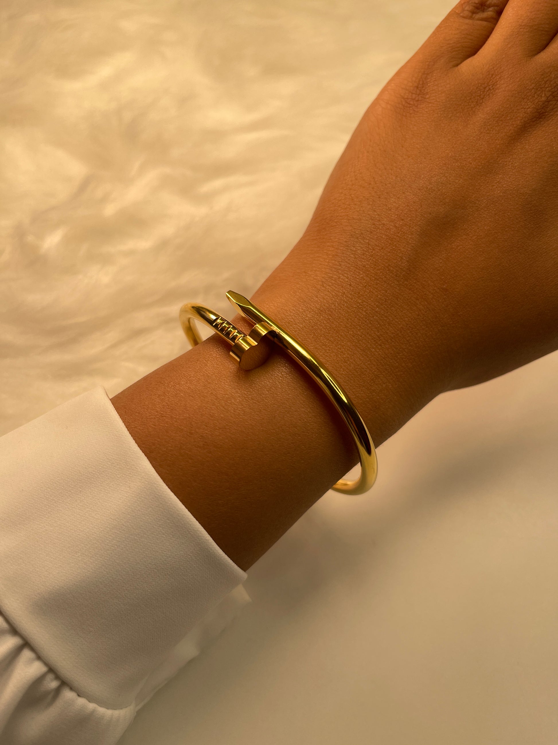 Gold Nail bracelet on a wrist with a blurred background