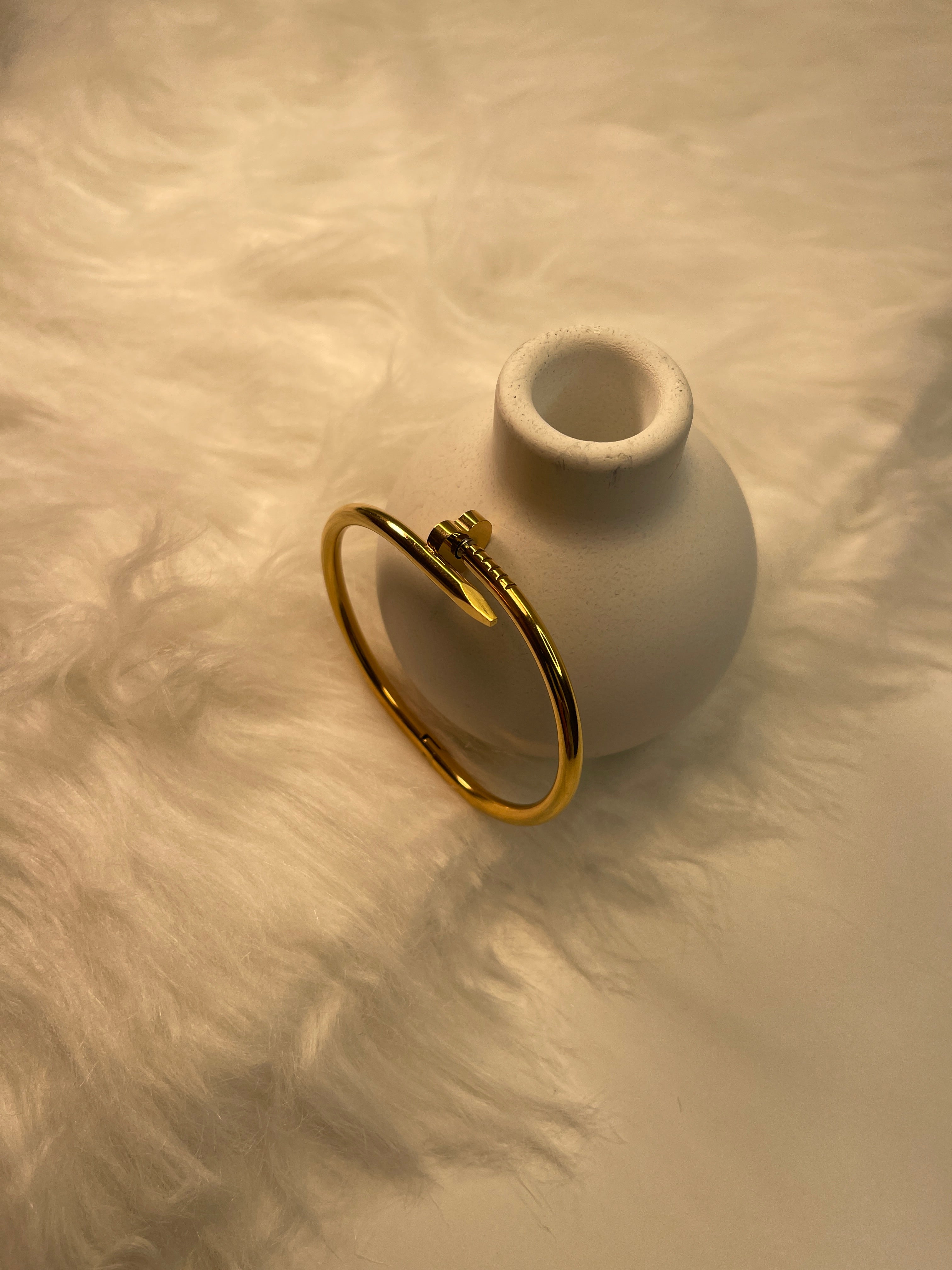 Gold Nail Bracelet on a textured beige surface