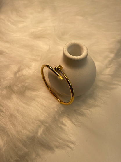 Gold Nail Bracelet on a textured beige surface