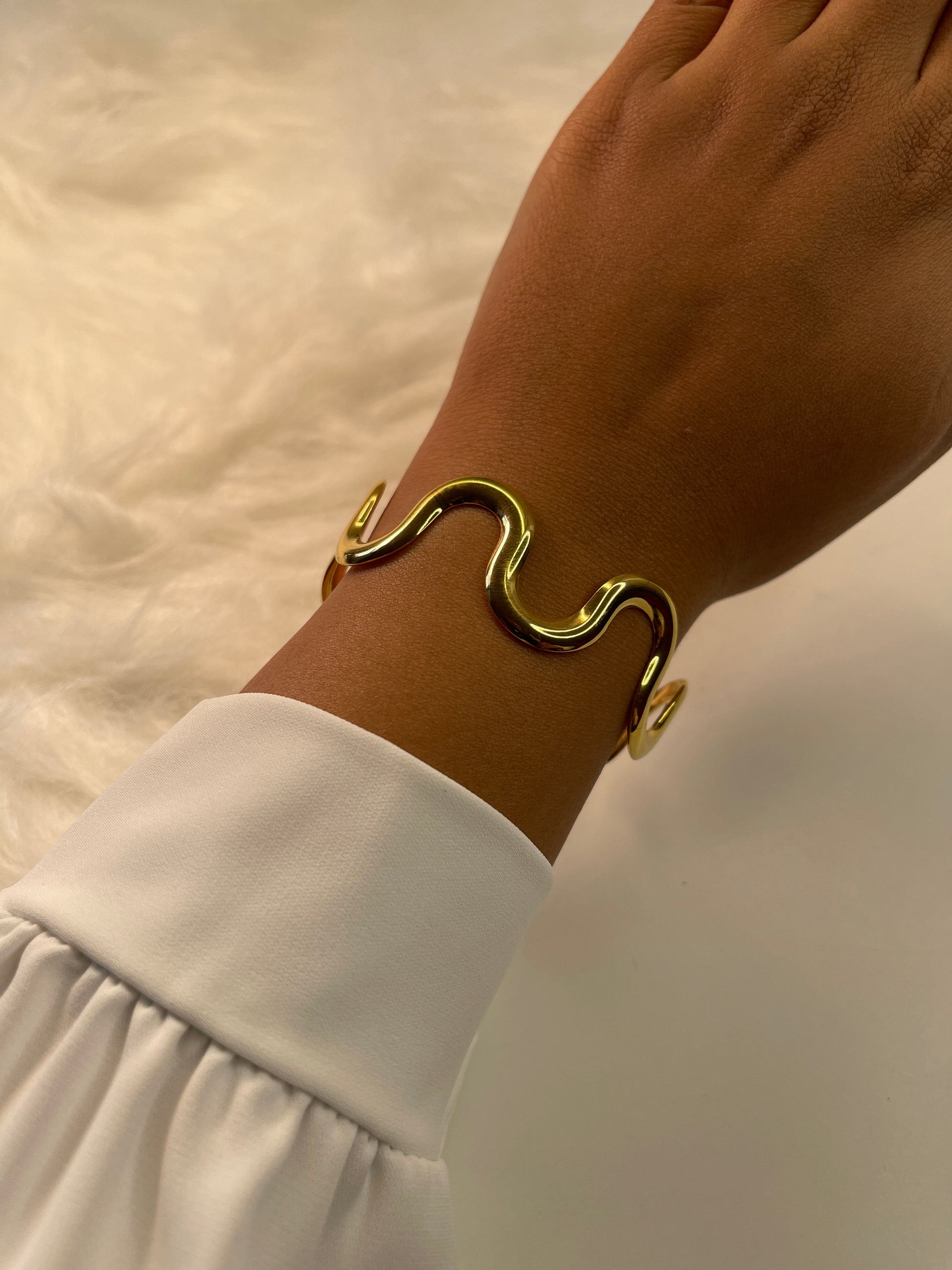 Gold bracelet on a wrist with a blurred background