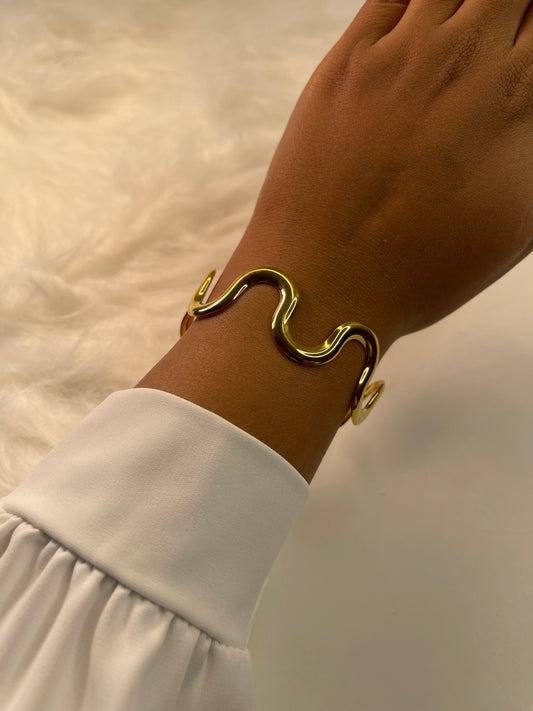 Gold bracelet on a wrist with a blurred background