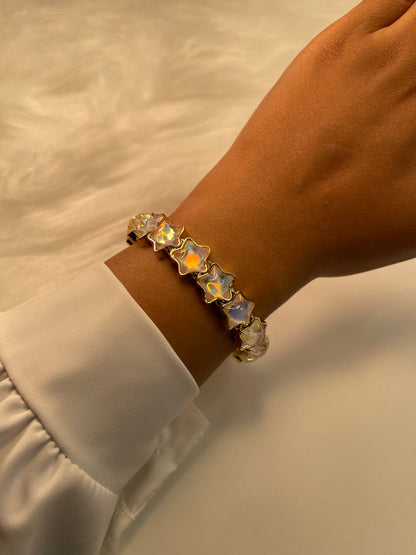 Bracelet with star-shaped gemstones on a wrist against a neutral background