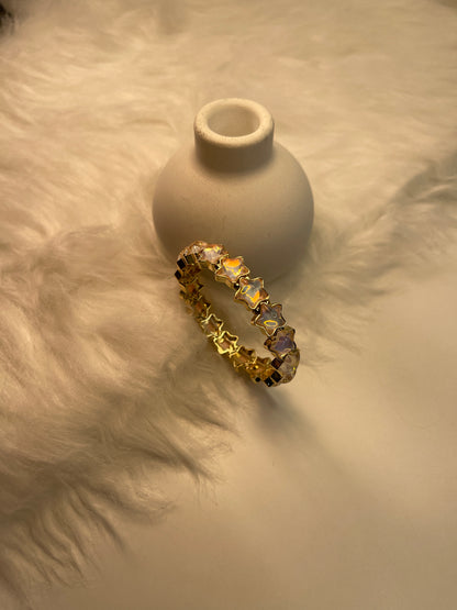 Gold Bracelet with embedded stones on a textured beige surface