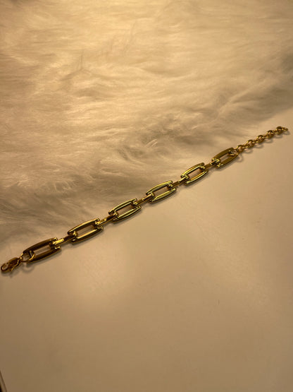 Gold link bracelet on a textured beige surface