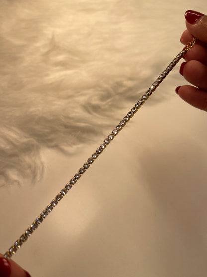 Close-up of a hand holding a diamond bracelet against a neutral background