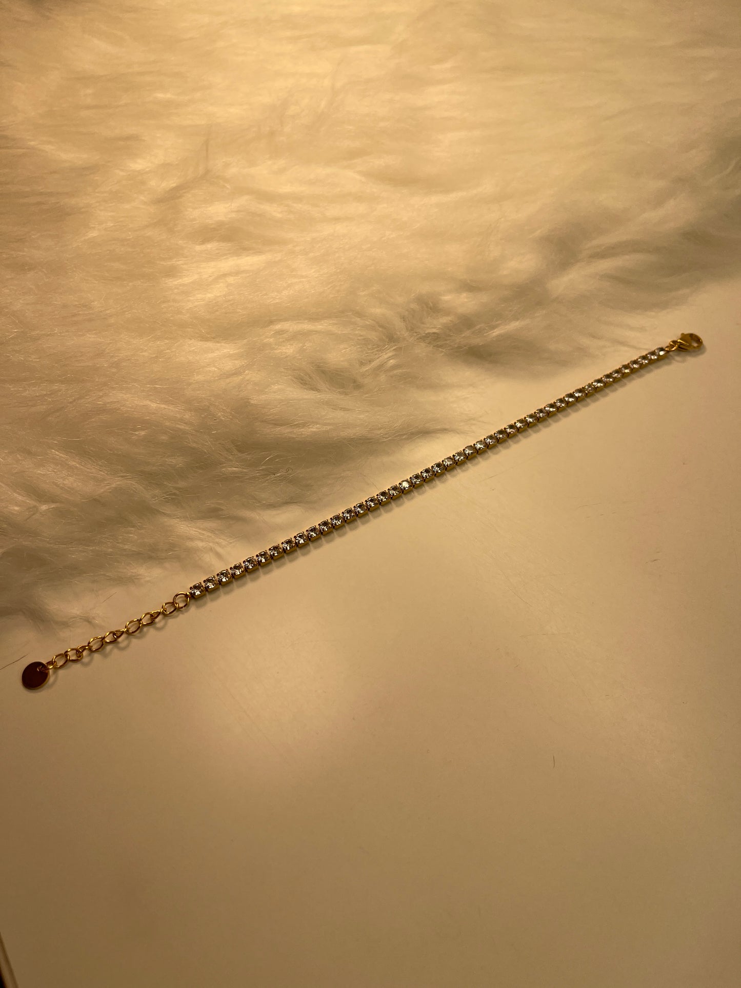 Gold chain with a dark bead on a textured beige background