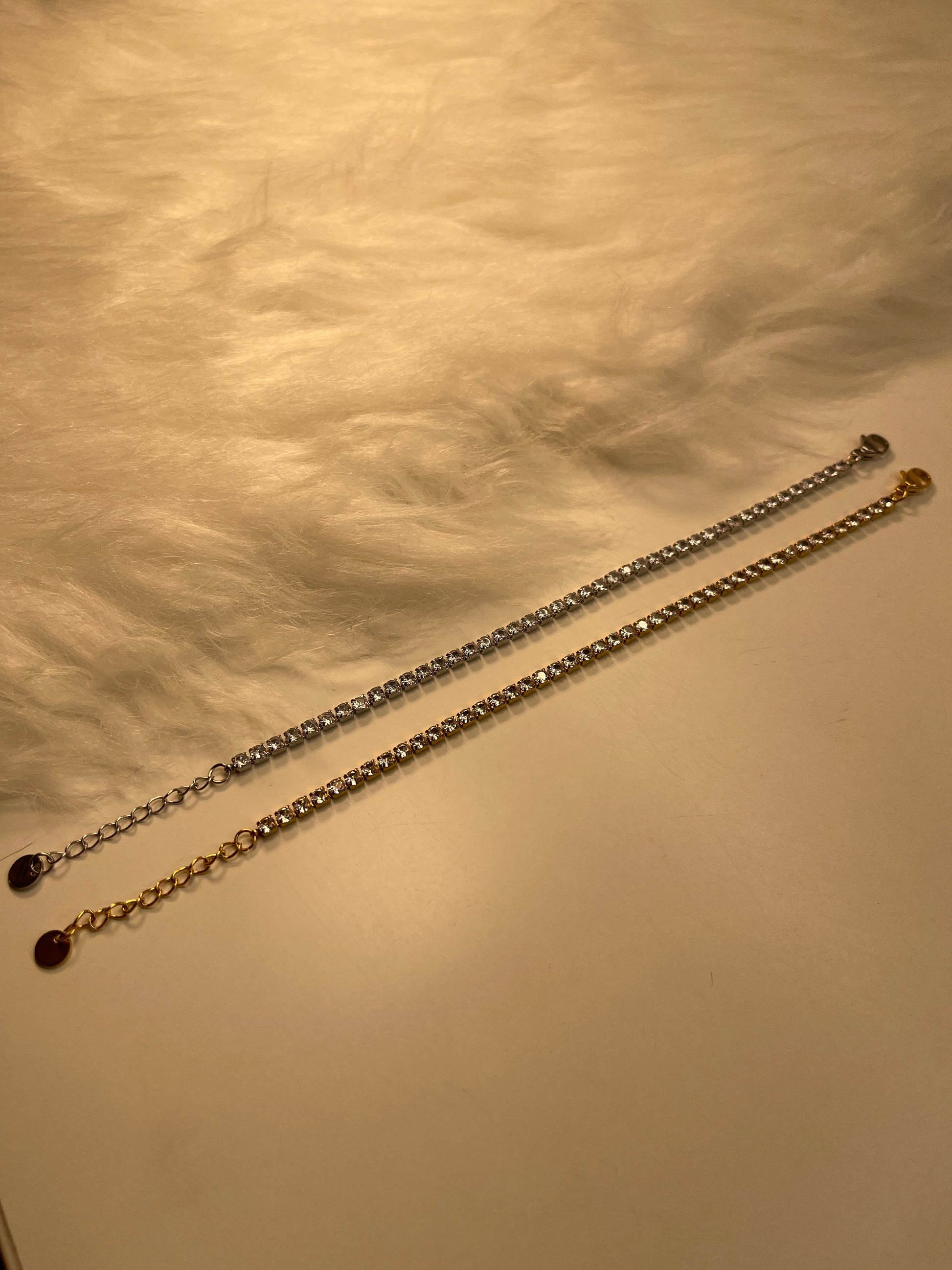 Two gold chains on a textured beige surface
