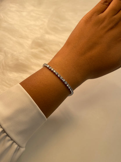 Silver bracelet on a wrist with a neutral background
