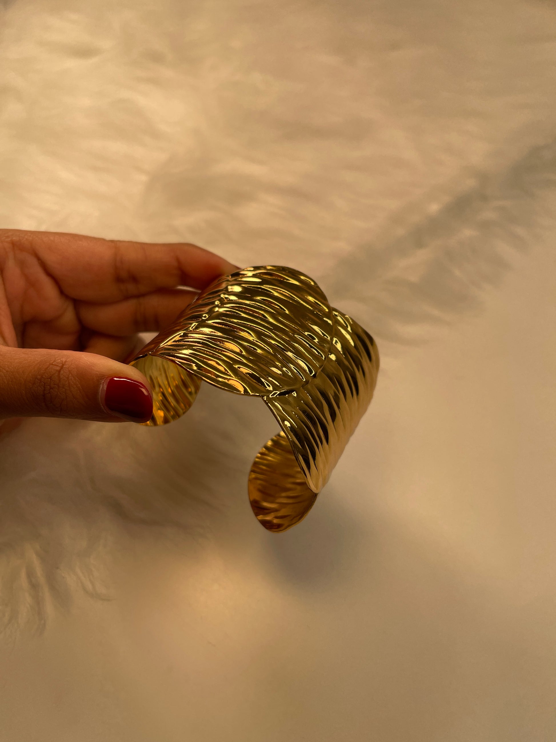 Gold leaf Bracelet held by a hand against a neutral background