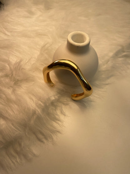 Gold Bracelet on a textured beige surface